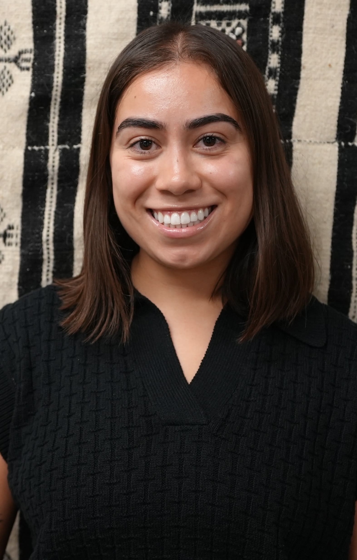 Marisol Ornelas, a Latina female in her 20s smiles for a photo. She has short shoulder length brown hair.