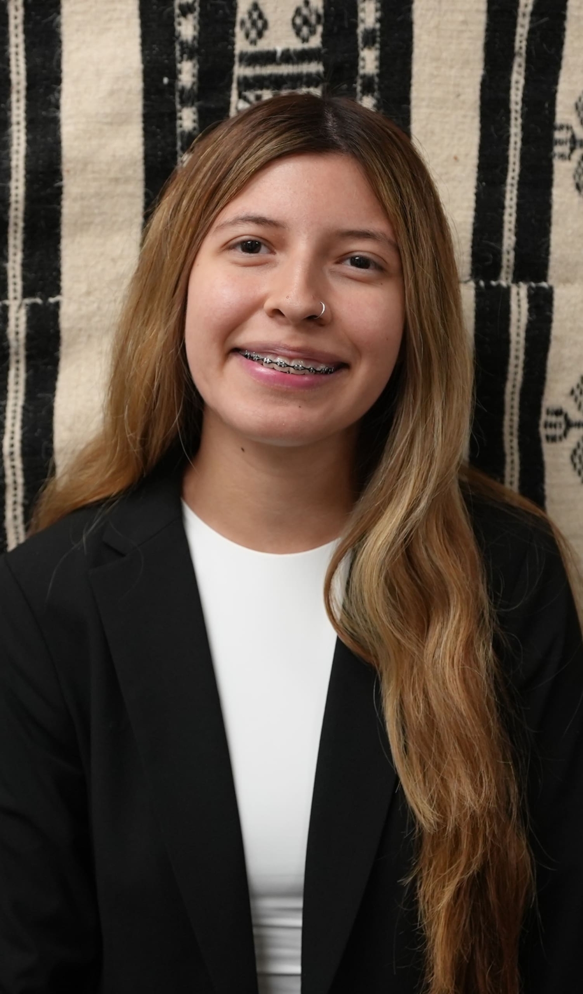 Nayely Martin, a Latina woman in her early 20s smiles for the photo. She has brown and dyed blonde hair as well as braces.