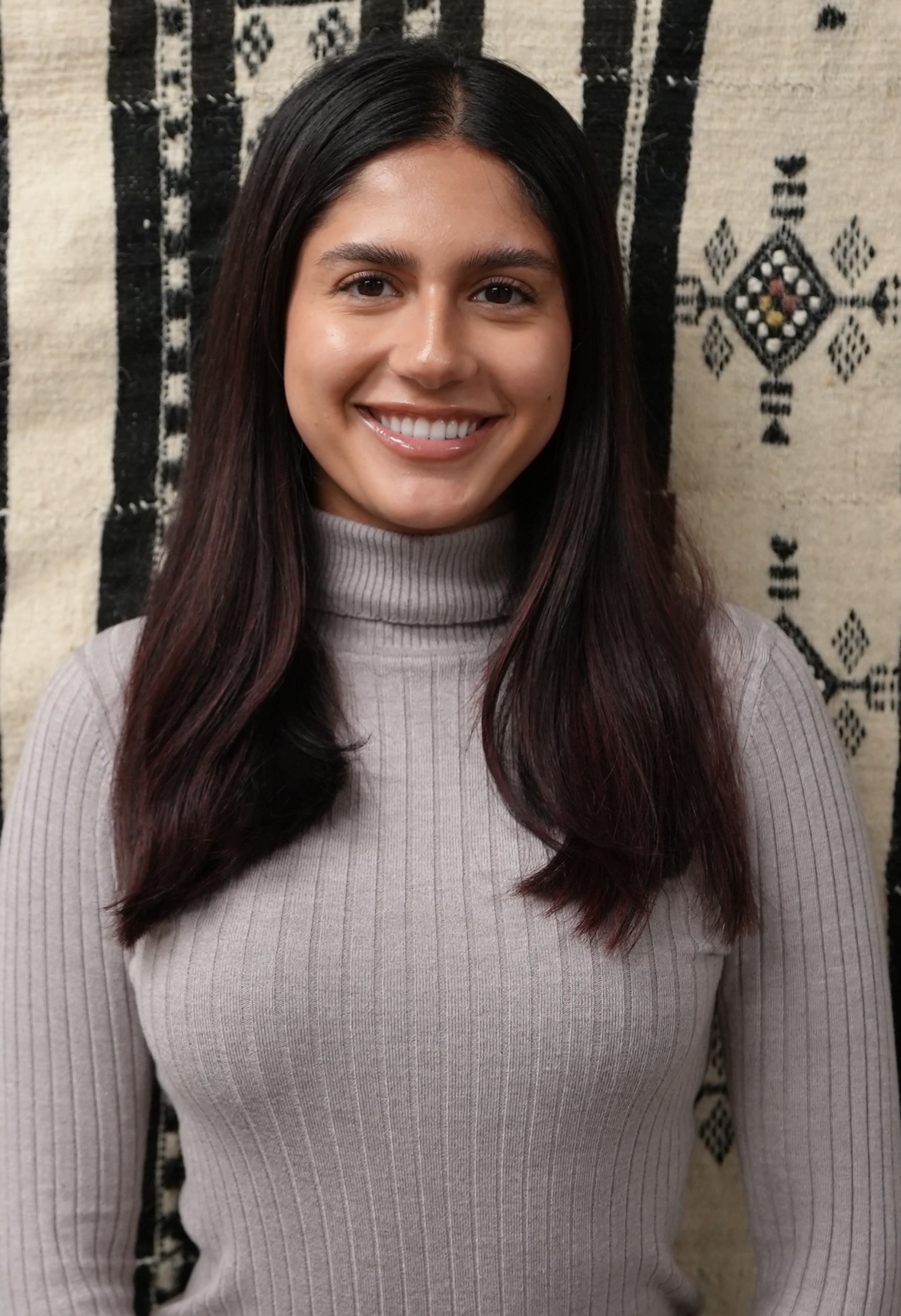 Vaneeza Moloo, female in her 20s smiles for the photo. She has short dark hair and brown eyes.